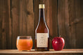Das Bild zeigt Land.Luft Apfelsaft, präsentiert zwischen einem Apfel und einem Glas Apfelsaft. Der naturbelassene, aromatische Saft eignet sich perfekt als Erfrischung.