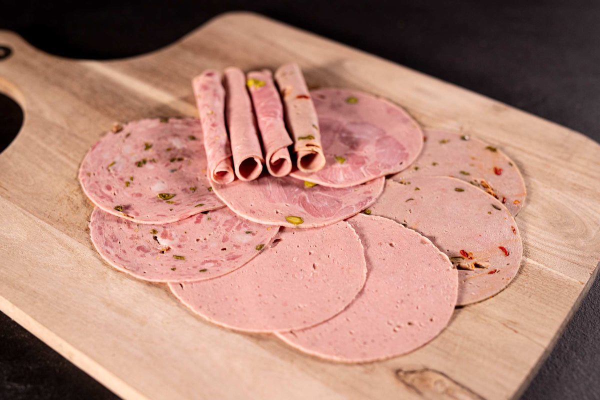 Auf dem Bild ist eine Auswahl gemischter Aufschnittwurst in Bio-Qualität zu sehen, darunter Lyoner, Paprikalyoner, Jagdwurst und Bierschinken. Alle aufgeschnitten und bereit für Brotzeit oder Wurstplatten.