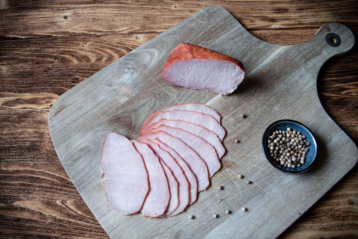 Das Bild zeigt Kaiserfleisch, gegart und mild geräuchert – ein kalorienarmer Schinken aus der Lende und dem Rücken. Die hochwertige Spezialität eignet sich perfekt für Brotzeit, Wurstplatten, Sandwiches oder als delikater Snack für Feinschmecker.