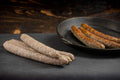 Auf dem Bild ist Land.Luft Bio Rinderbratwurst zu sehen. Einmal frisch und einmal gebraten angerichtet, saftig und aromatisch. Ideal zum Grillen und zum Braten.