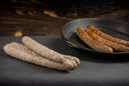 Auf dem Bild ist Land.Luft Bio Rinderbratwurst zu sehen. Einmal frisch und einmal gebraten angerichtet, saftig und aromatisch. Ideal zum Grillen und zum Braten.