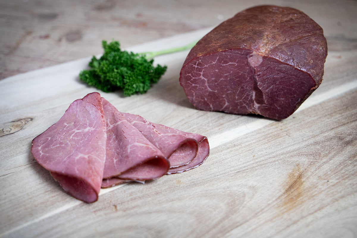 Das Bild zeigt aufgeschnittenen Bio Rinder-Saftschinken (ca. 180–220 g). Die hochwertige Spezialität überzeugt mit zarter Konsistenz und eignet sich perfekt für Brotzeit, Wurstplatten oder als delikater Snack für Feinschmecker.