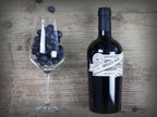 Das Bild zeigt eine Flasche Groszer Wein Saybritz neben einem dekorativen Weinglas mit Weintrauben. Die elegante Präsentation unterstreicht die Qualität des Weins und eignet sich perfekt für Weinliebhaber, besondere Anlässe oder als Geschenk.