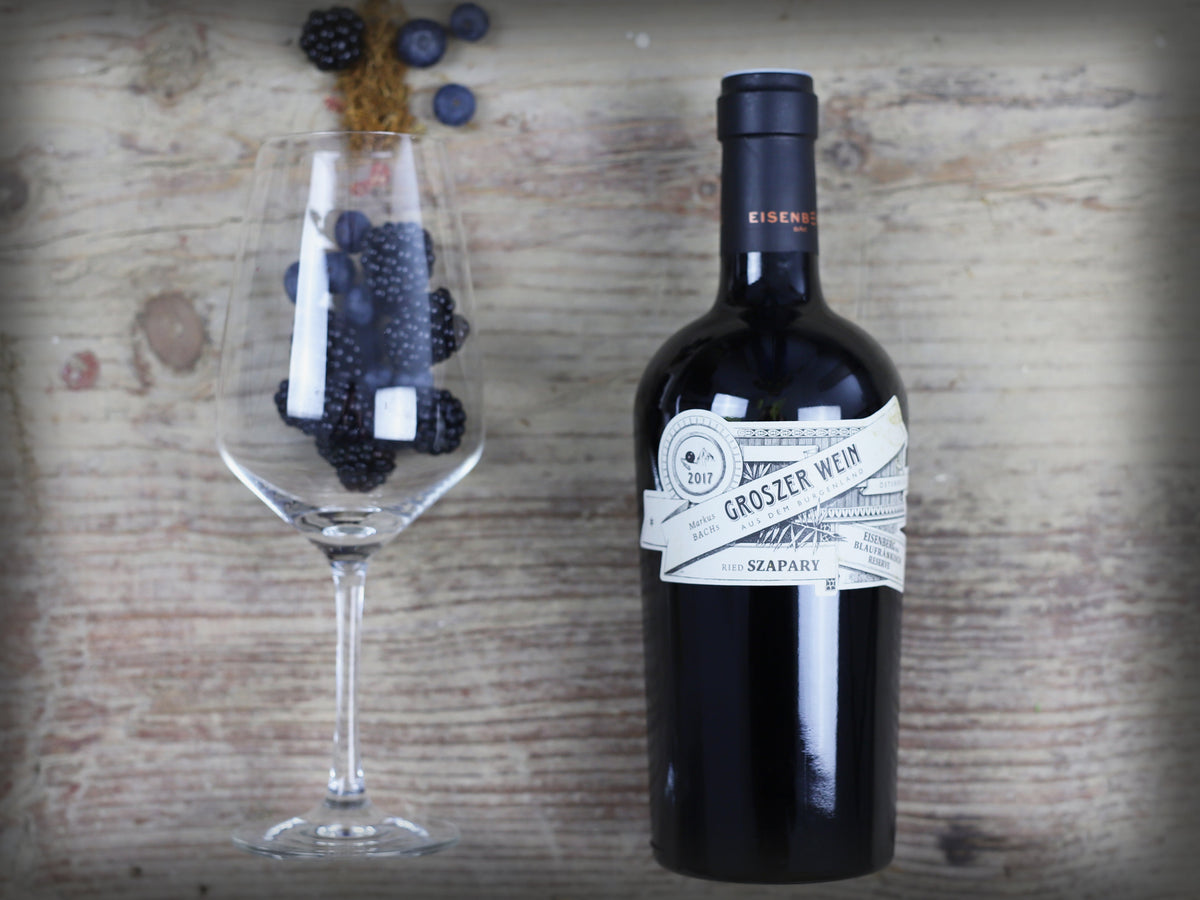 Das Bild zeigt eine Flasche Groszer Wein Szapary neben einem dekorativen Weinglas mit frischen Blaubeeren und Brombeeren. Die elegante Präsentation unterstreicht die Qualität des Weins und eignet sich ideal für Weinliebhaber, besondere Anlässe oder als Geschenk.