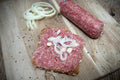 Auf dem Bild ist Zwiebelmettwurst in Bioqualität zu sehen – fein gewürzt mit Zwiebeln und ausgewählten Gewürzen, ideal als Brotzeit, Snack oder für herzhafte Gerichte